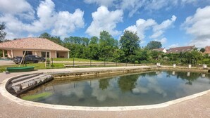 A swimming pool with a tiled deck, a covered seating area, and a grassy area with trees. - Beautiful home in Bezinghem with WiFi (Bezinghem)