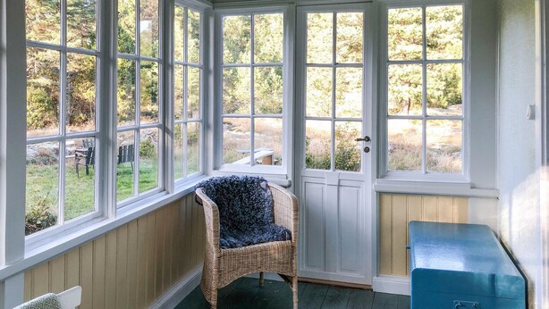 A conservatory with a wicker chair and a blue cabinet.