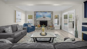 A modern living room with a fireplace, comfortable seating, and a large painting above it. - Luxury 6BR Villa with Heated Pool & Private Theater (Valrico)