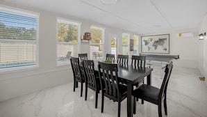 A dining area with a large table, multiple chairs, and a projector screen. - Luxury 6BR Villa with Heated Pool & Private Theater (Valrico)