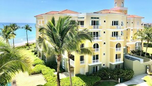 Un hotel de varios pisos con balcones, una torre con cúpula y vista al mar.