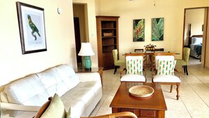 Una sala de estar con sofá, sillas, una mesa de centro y un comedor con mesa y sillas.