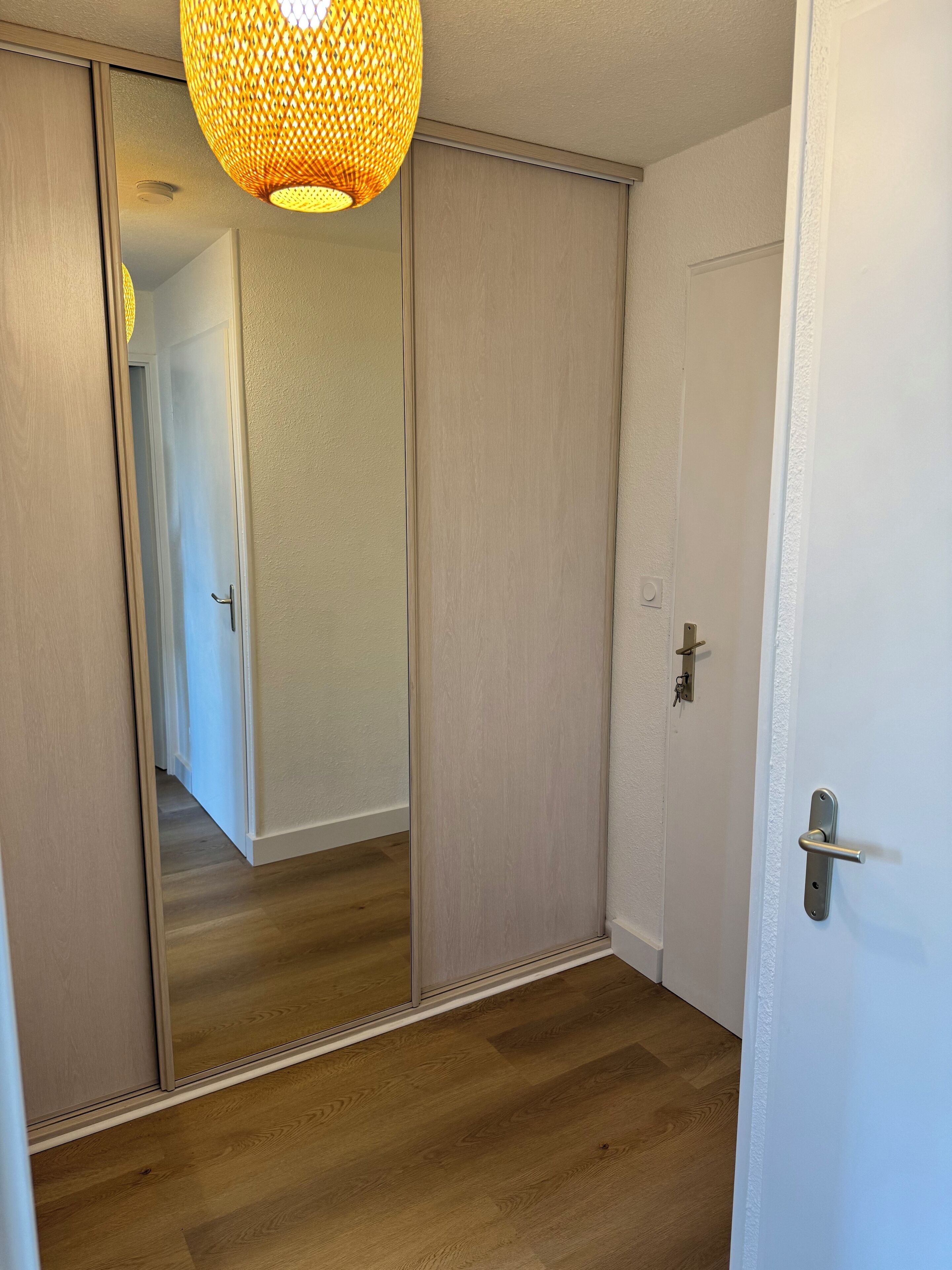 A room with a sliding door, a wooden floor, and a hanging light fixture.