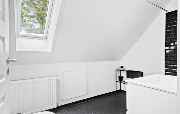 A modern bathroom with a skylight, white walls, a black countertop, and a white bathtub. - Stunning home in Harboøre with WiFi (Harboøre)