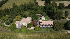 Luchtbeeld van een landgoed met een groot huis, een schuur en veel groen eromheen.