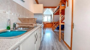 Una cocina estrecha con un lavamanos empotrado, muebles de madera y vistas a un comedor.