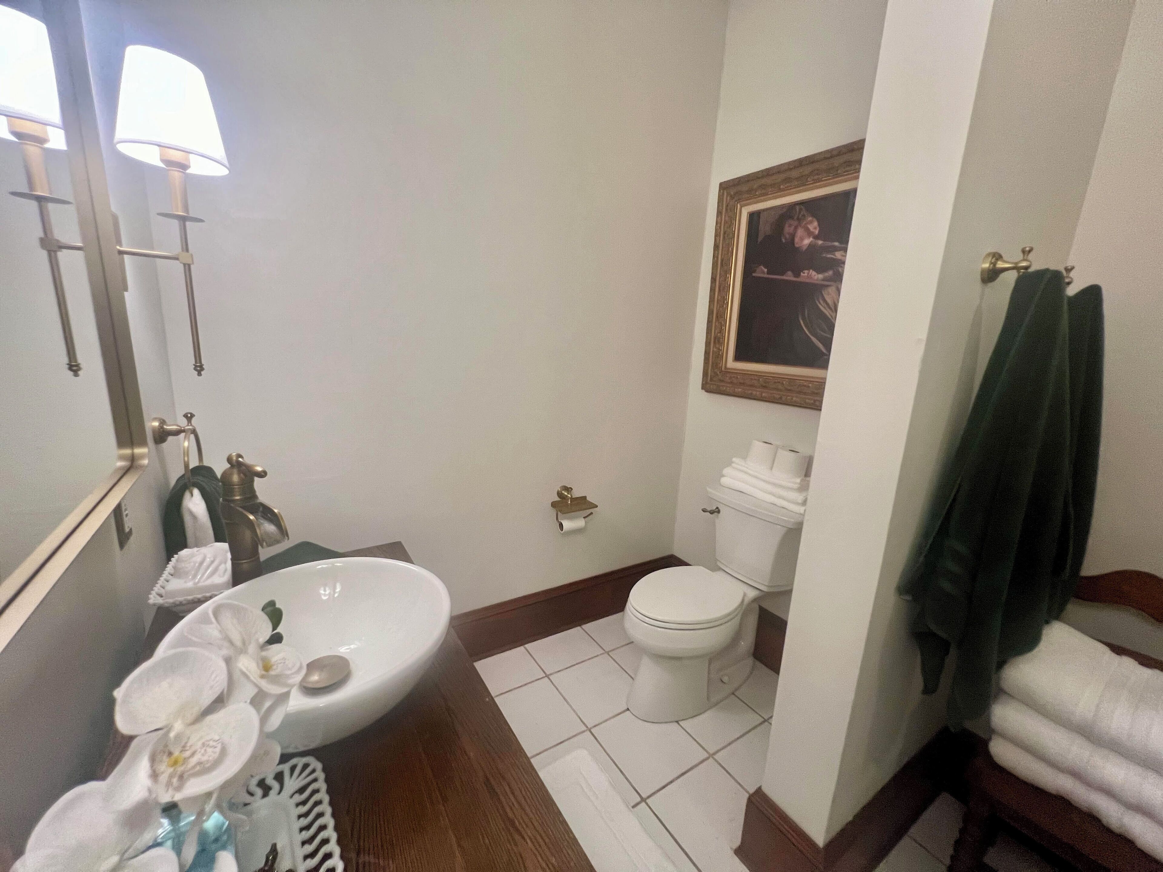 A bathroom with a white sink, mirror, toilet, and a towel rack.