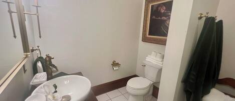 A bathroom with a white sink, mirror, toilet, and a towel rack.
