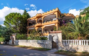 A multi-story building with balconies, a stone wall, and a gate. - Beach front apartment in Rovanjska (Rovanjska)