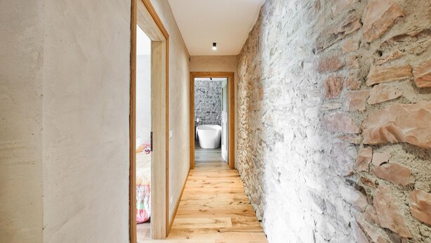 A narrow hallway with wooden flooring and a stone wall on one side. - 3 bedroom awesome home in Lamon (Lamon)