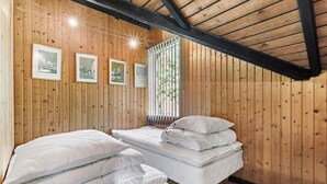 A wooden-paneled room with two beds, a window with blinds, and three framed pictures on the wall. - 2 bedroom lovely home in Melby (Melby)