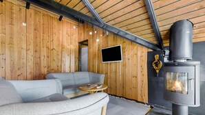A cozy room with a sofa, a small table, a TV, and a wood-burning stove. - 2 bedroom lovely home in Melby (Melby)