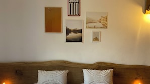 A neatly made bed with a quilted white duvet, two pillows, and folded towels on a wooden headboard. - The Pink House of Riso Amaro In the painted village Legro  of Orta San Giulio (Orta San Giulio)