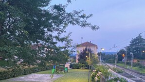 A well-maintained grassy area with a playground, benches, and a flower bed. - The Pink House of Riso Amaro In the painted village Legro  of Orta San Giulio (Orta San Giulio)