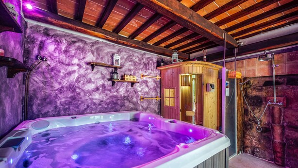 Ett bubbelbad med en trähusliknande byggnad och väggar av sten.