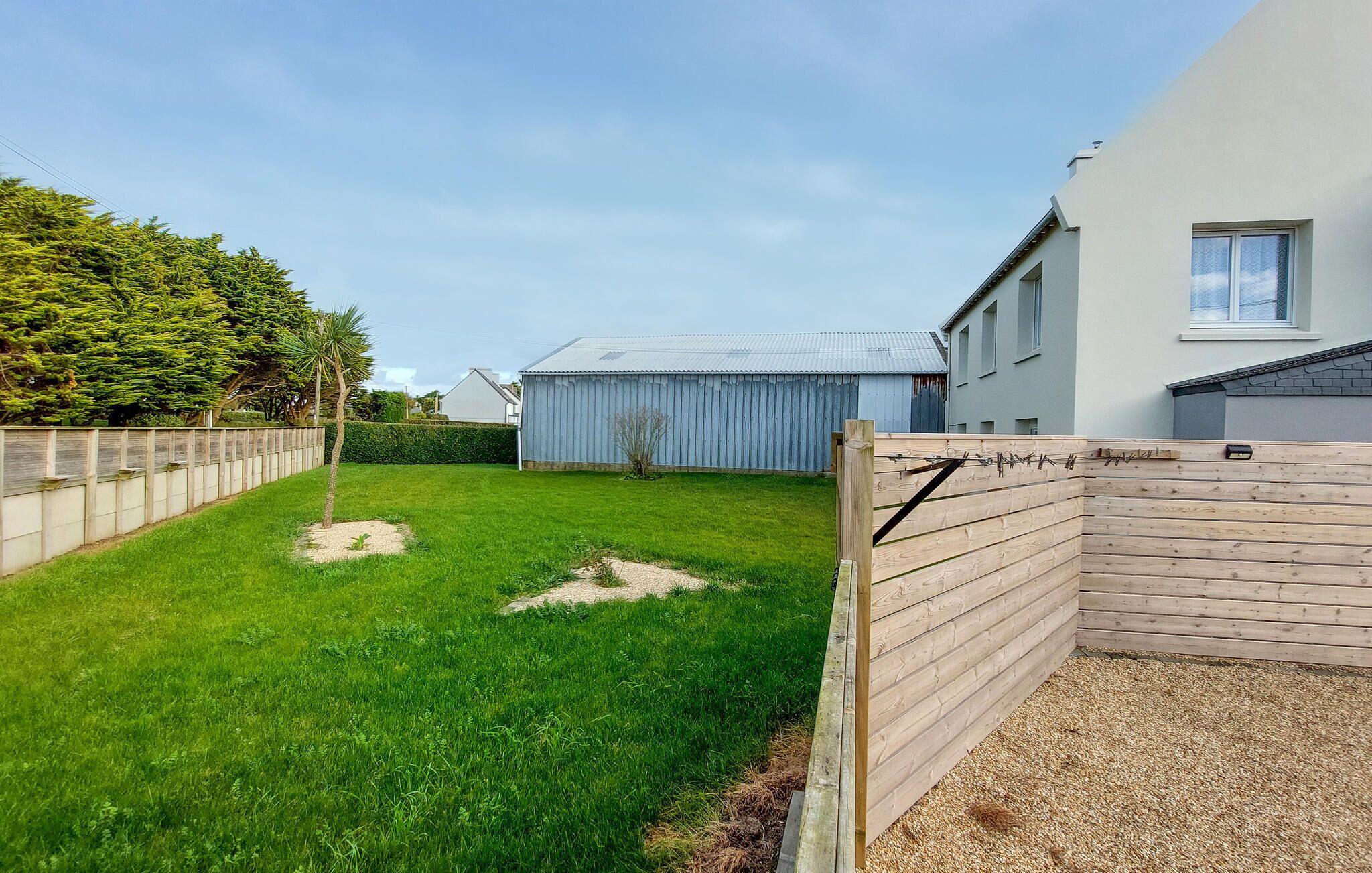 A fenced backyard with a grassy lawn, a wooden fence, and a metal shed.