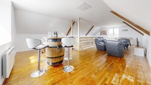 A spacious loft with a wooden floor, a bar area with stools, and a seating area with sofas. - Beautiful apartment in Kerlouan with WiFi (Kerlouan)