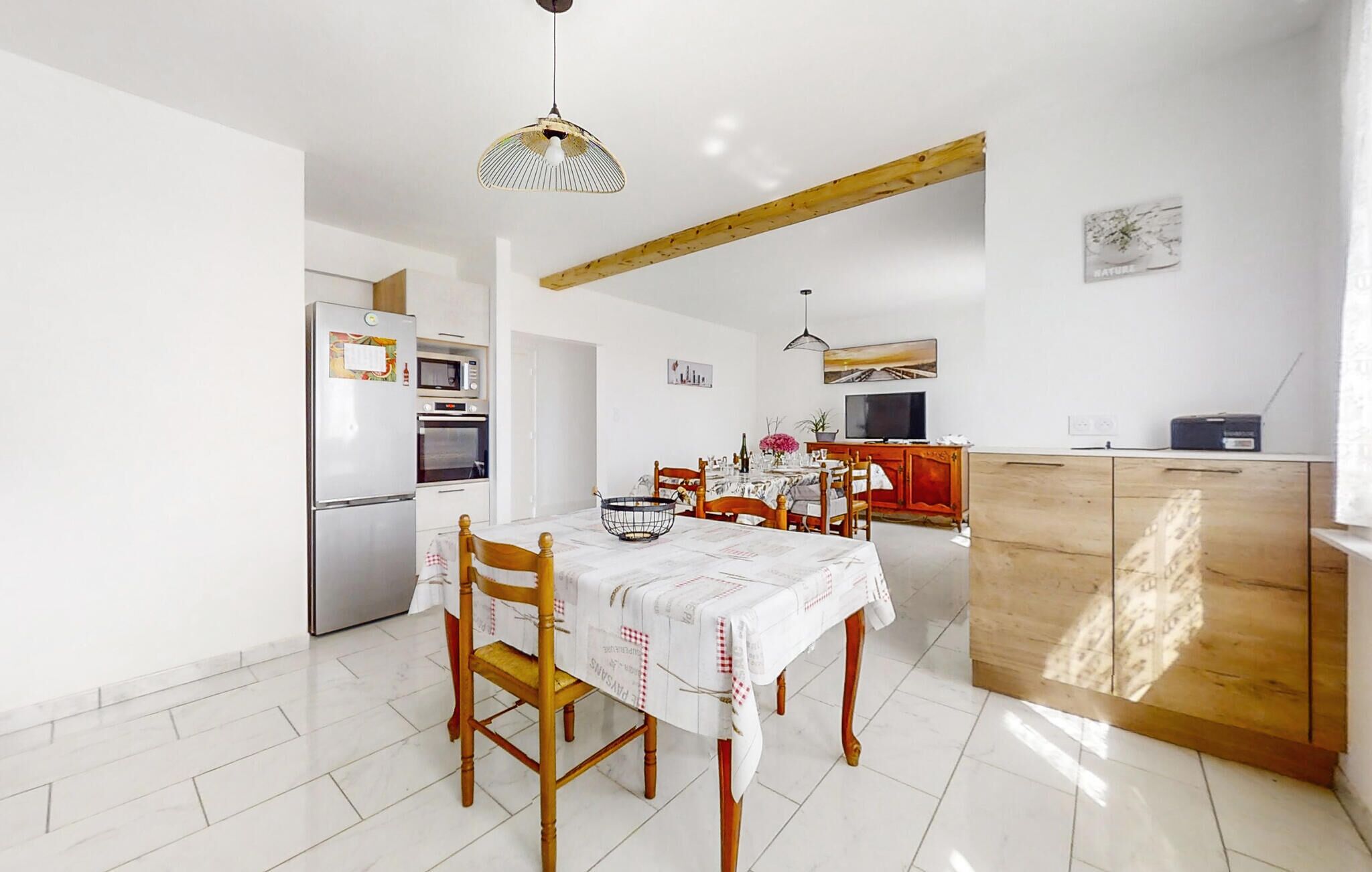 A compact kitchen with a dining area, featuring a refrigerator, microwave, oven, wooden cabinets, and a dining table with chairs.