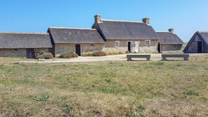 A row of stone cottages with thatched roofs, a gravel path, and a bench in a rural setting. - Beautiful apartment in Kerlouan with WiFi (Kerlouan)