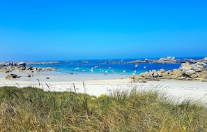 Ein Strand mit klarem, blauem Wasser, Felsformationen und Booten.