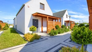 A modern two-story house with a sloped roof, a wooden deck, and a well-maintained garden.