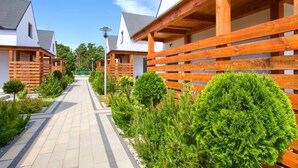A pathway leading to a row of modern, wooden-framed buildings with a clear sky above.