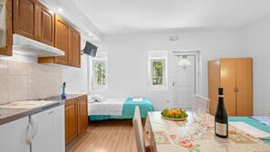 A compact kitchen with wooden cabinets, a built-in oven, and a dining area with a table set for two. - Beautiful apartment in Lozovac with WiFi (Lozovac)