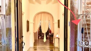 A hallway with a checkered floor leading to a room with a bed and curtains. - Room #1 two blocks from the Malecon (La Paz)