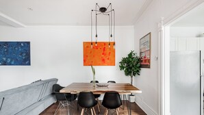 Un comedor con una mesa de madera, sillas negras, un sofá gris y una lámpara colgante moderna.