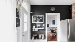 Una cocina moderna con pared negra, armarios blancos y un menú en pizarra que ofrece café y té.