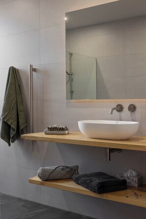 Ein modernes Badezimmer mit einem großen weißen Waschbecken, einem Handtuchhalter und einem Spiegel über dem Waschbecken.
