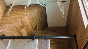 Une pièce avec un plancher en bois, un filet blanc fixé au plafond et une barre métallique noire.