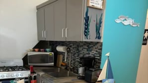 Une cuisine dotée d’un îlot central, de tabourets de bar, d’une cuisinière, d’un four à micro-ondes et d’un évier.