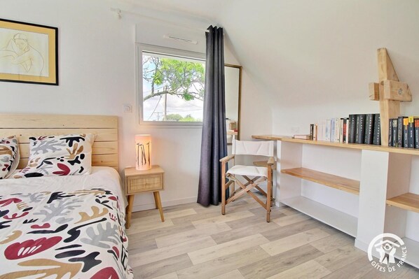 Un dormitorio con cama, mesita de noche, silla y estantería.