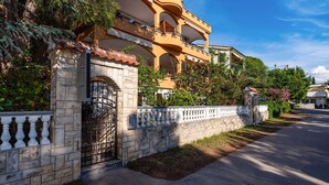 Un bâtiment traditionnel avec une façade en pierre, une entrée fermée par un portail et un balcon.
