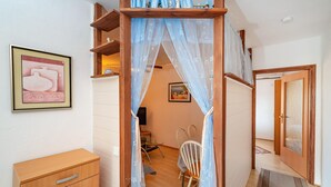 Une pièce comprenant une armoire en bois, une chaise, un bureau et un lit à baldaquin.