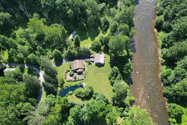 An aerial view of a property with a river, surrounded by dense greenery.
