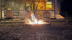 A house with a porch, a fire pit, and two chairs.