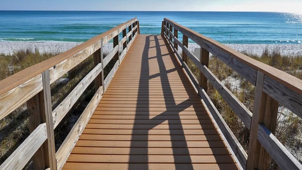 A wooden boardwalk leading to a beach with clear blue water and sandy shore. - Sunshine Oasis | Private Pool | Dog-Friendly | My Beach Getaways (Gulf Breeze)