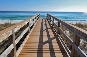 A wooden boardwalk leading to a beach with clear blue water and sandy shore. - Sunshine Oasis | Private Pool | Dog-Friendly | My Beach Getaways (Gulf Breeze)