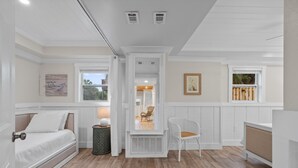 A room with a bed, a chair, a small table with a lamp, a window, and a picture on the wall. - Sunshine Oasis | Private Pool | Dog-Friendly | My Beach Getaways (Gulf Breeze)