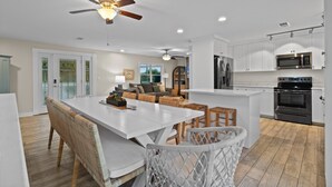 A modern kitchen with white cabinets, a stainless steel refrigerator, and a built-in oven. - Sunshine Oasis | Private Pool | Dog-Friendly | My Beach Getaways (Gulf Breeze)