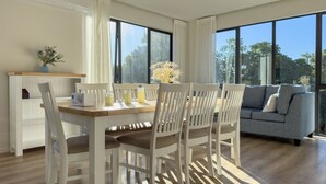 A modern living room with a dining area, large windows, and a sofa.