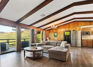 Relax in this spacious living room with a high ceiling and large window offering a view of the surrounding landscape.