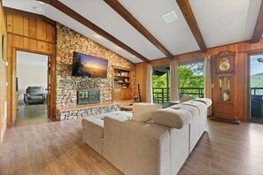 Cozy living room with a fireplace, comfortable sofa, and large balcony with a view.