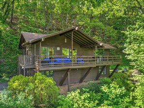 Situated in a lush forest, this cabin offers a balcony with outdoor seating and a vantage point over the surrounding greenery.