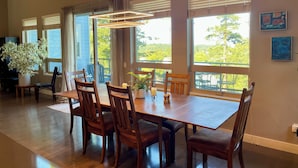 Uma área de refeições com uma mesa grande, cadeiras de madeira e um lustre.