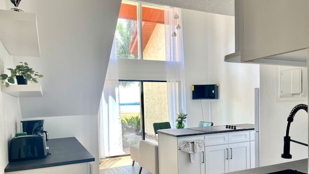 A modern kitchen with a built-in island, a dining area with a view, and a large window. - Home near Sea world/Universal/Convention center (Orlando)