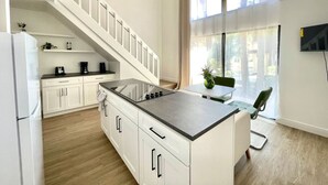A modern kitchen with a central island, white cabinetry, and a staircase leading to an upper level. - Home near Sea world/Universal/Convention center (Orlando)