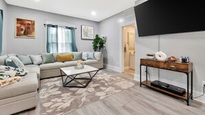 A living room with a sofa, coffee table, and TV stand. - Wichita home, by the river, spacious 9 beds-game room with pool table, 1gb Wi-Fi (Wichita)